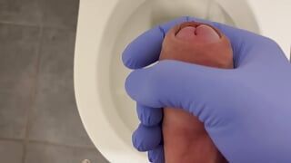 Masturbando médico em um banheiro com luvas de látex