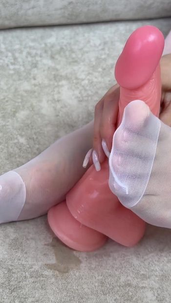 Schönes mädchen in weißen nylonstrümpfen gibt gummi-dildo footjob