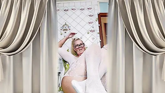 Жизнерадостная домохозяйка Лукерия флиртует в открытом, прозрачном белом комбинезоне на кухне.