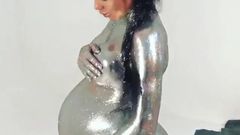 Salope nue enceinte avec de la peinture pour le corps argentée