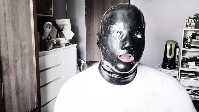 A guy in a latex mask with tubes for his nose jerks off and cums