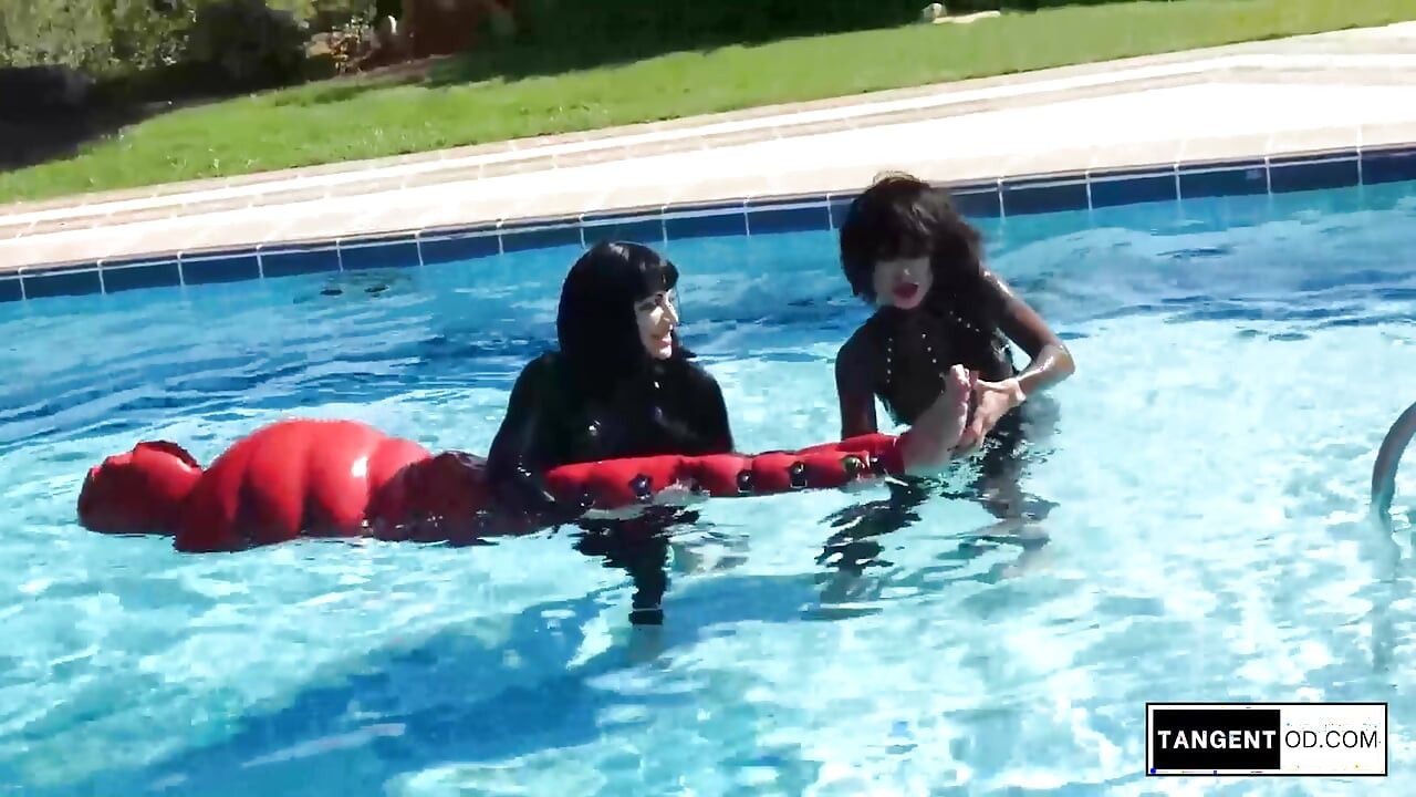 TANGENTOD Women in Black Catsuits Float Red Latex Encased Figure on Inflatable Rubber Pool Toy