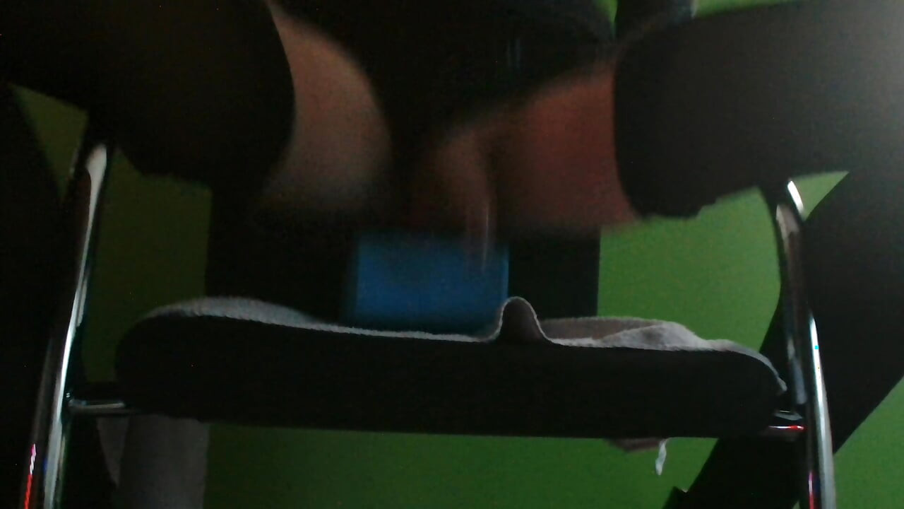 Riding 22 cm long dildo on chair in latex and heels.