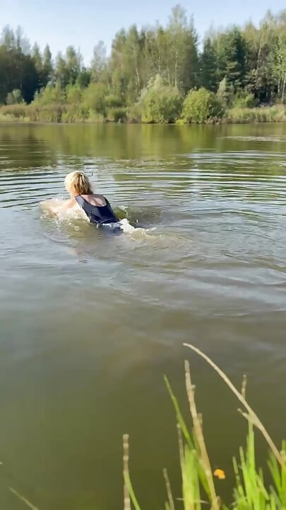 Trans djevojka pliva u jezeru u plavoj sportskoj haljini. Wetllok trans djevojka mokra.