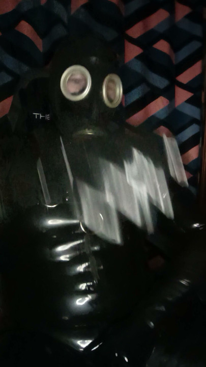 A guy in rubber pulls on a gas mask