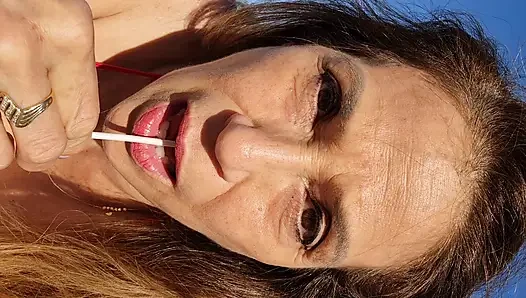 Melissa Johnson sucks and licks a cherry lollipop on the .beach