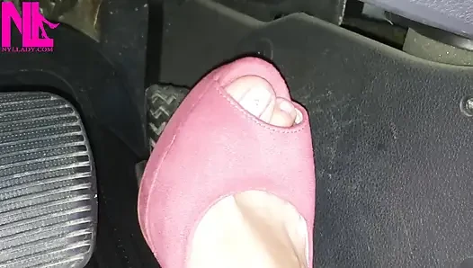 Barfuß fahren und revving in lebhaften rosa sandalen mit hohen absätzen
