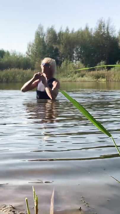 青いスポーツドレスを着て湖で泳ぐトランスジェンダーの女の子。ウェトロックトランスガールウェット。