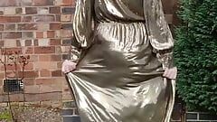 Sissy travestiet buitenshuis in gouden metallic glanzende jurk