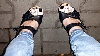 Crossdresser pronkt met haar mooie voeten in wiggen met hoge hakken in het openbaar
