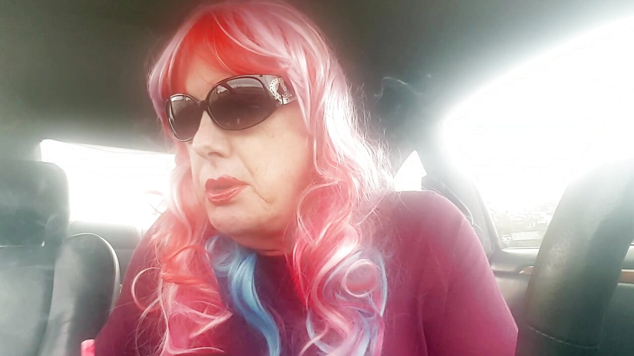 Зряла TG CD с перука с дъга и кожени ръкавици пуши VS120s като професионалистка в колата си