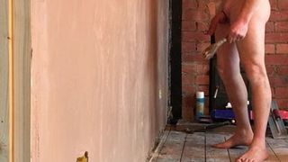 Construtor nudista revirando a parede nua