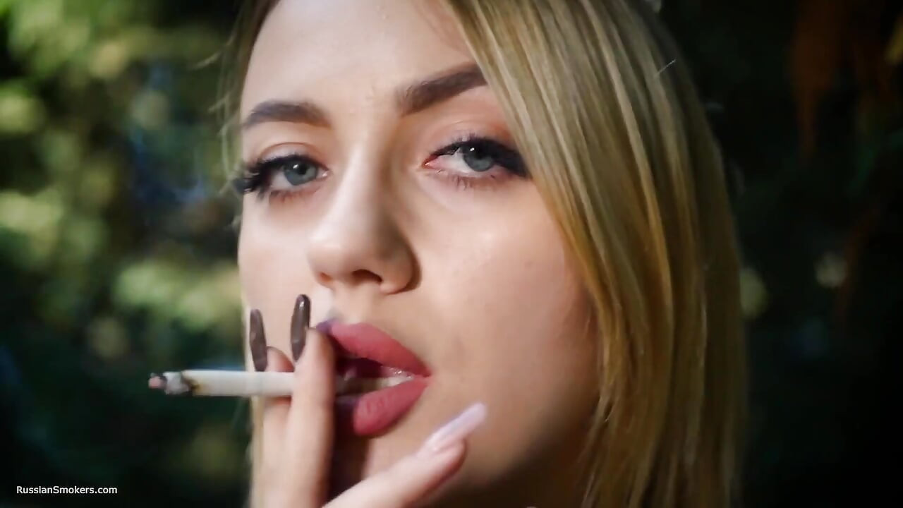 Gorąca blonde babe palenie jeden czarnych papierosów w naturze