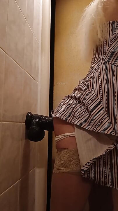 Posłuszna dziwka jeździ dildo montowane na ścianie w toalecie