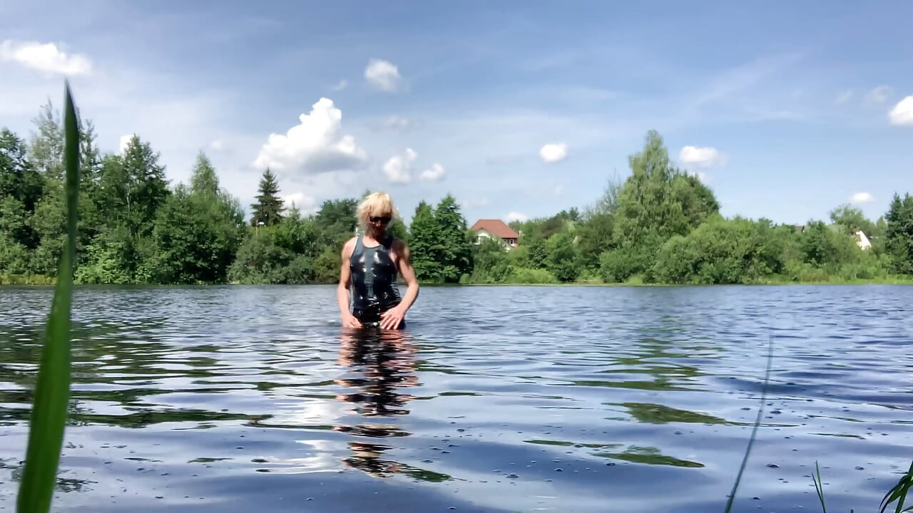 Trans djevojka Alexa Cosmic pliva i igra se u jezeru u crnoj kratkoj i plavoj majici
