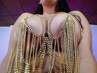 Seksowna bogini bawi się swoimi dużymi piersiami w łańcuchowym stroju.