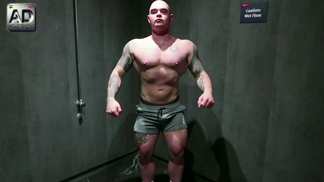 ジムのジョックが筋肉を見せつけ、公衆トイレのクルージングでカットされていない大きなチンポで遊ぶ