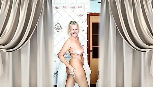 A mature blonde in a knitted dress shows off her curves in a home environment.