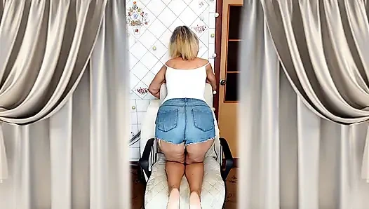 Cheerful housewife Lukerya flirts in the kitchen in tight denim shorts.