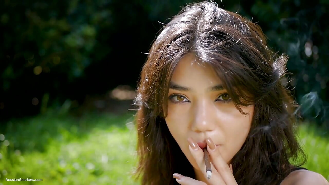 Arina está fumando um cigarro preto ao ar livre
