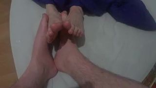 two friends playing footsies with naked feet on the bed