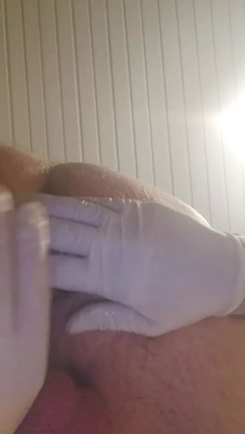 Wearing surgical gloves and inserting a butt plug into the anus