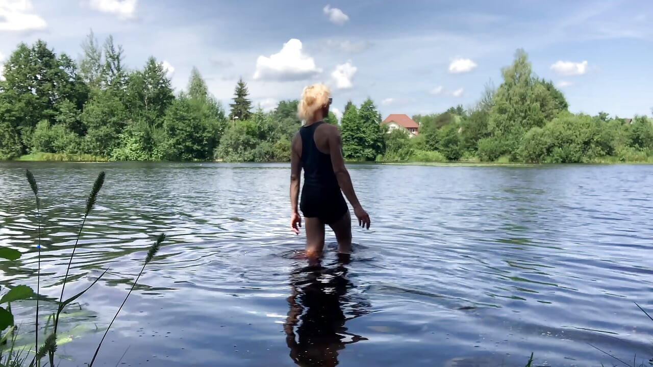 Trans djevojka Alexa Cosmic pliva i igra se u jezeru u crnoj kratkoj i plavoj majici