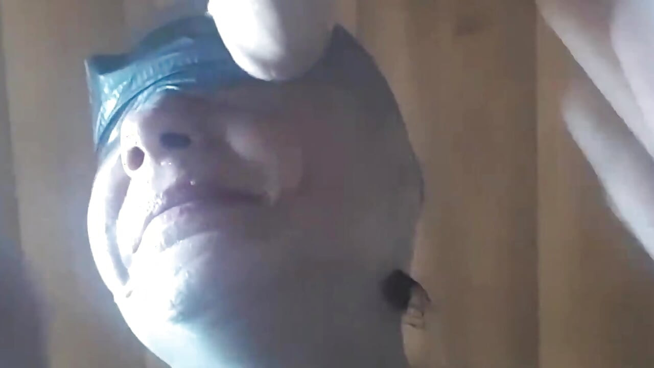 Δεύτερη άποψη μιας milf με κουκούλα σε νάιλον, με δεμένα μάτια με κολλητική ταινία, με πρόσωπο και χύσιμο στο στόμα