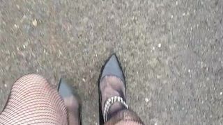 Caminar con zapatos negros con correa en el tobillo, medias de rejilla y falda (pov)