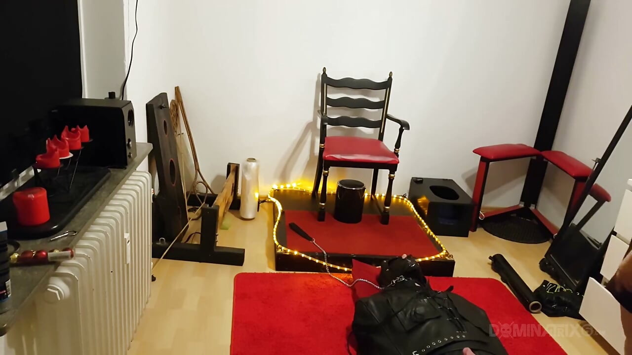 Kurvikas ruskeaverikkö Dominatrix komentaa sidottua orjaa fetissityrmässä