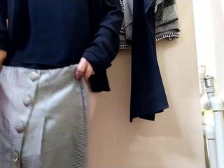 Русская мамочка меряет юбки в примерочной комнате в торговом центре