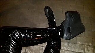 Een travestiet op platformschoenen met hoge sleehak en latexlegging loopt 's nachts door de straten