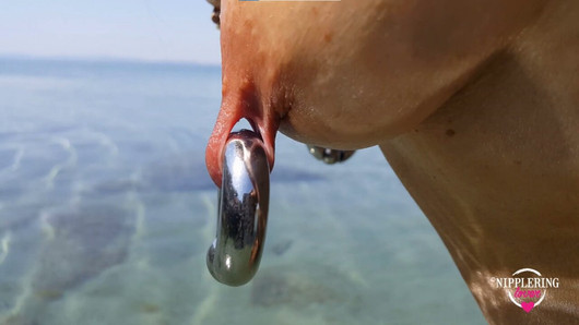 Tepelaarliefhebber, geile milf met extreem doorboorde tepels en poesje verwisselt tepelringen op het openbare strand