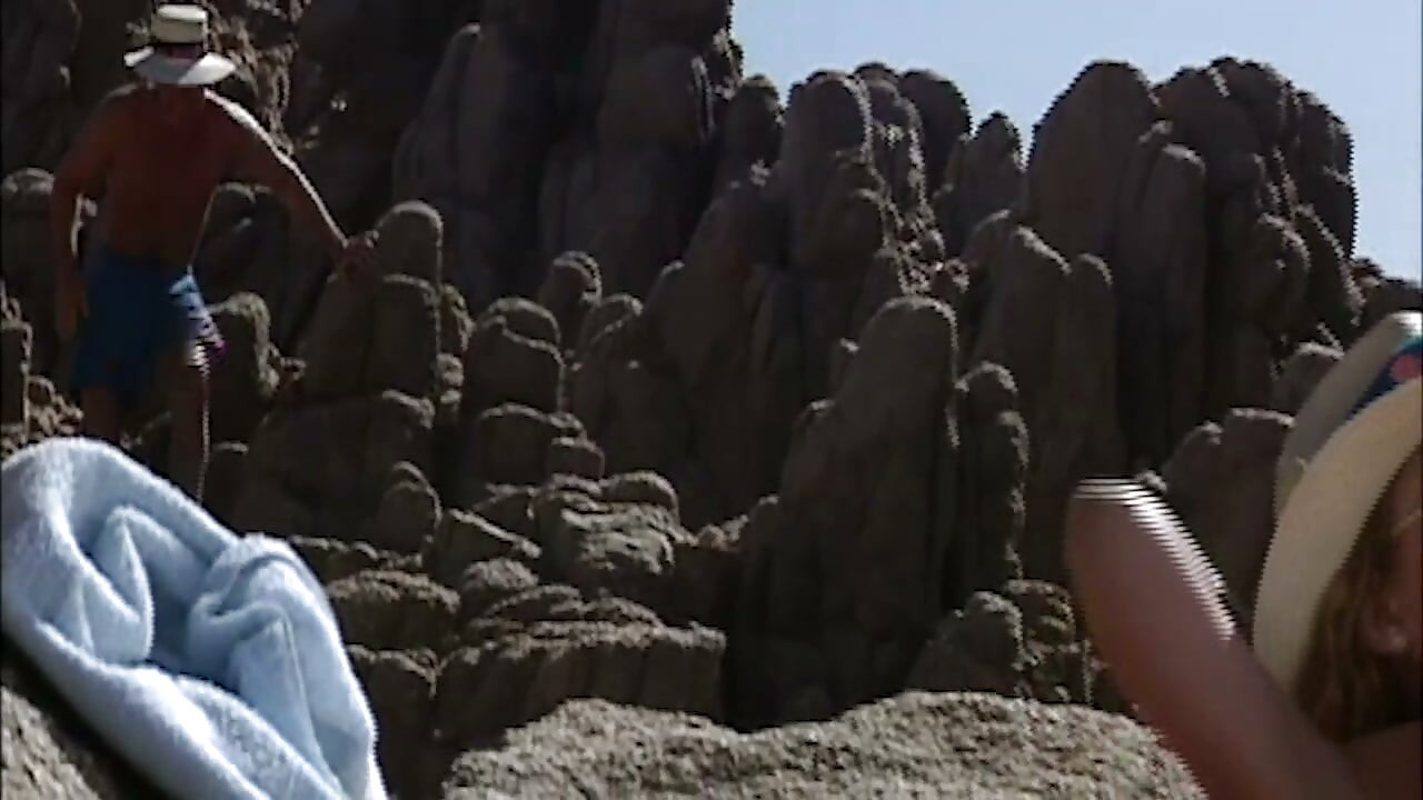 Ella yace desnuda en la playa mientras él la observa