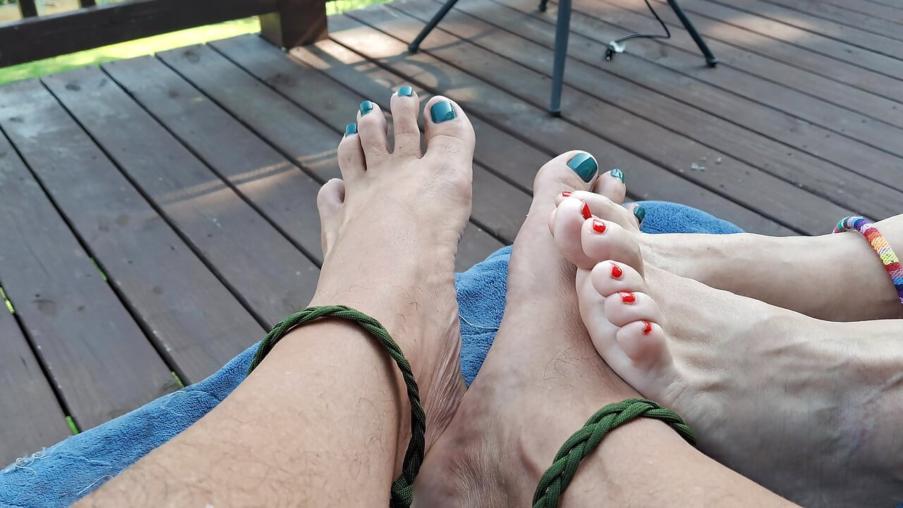 Barefoot couple with painted toes plays footsie outside