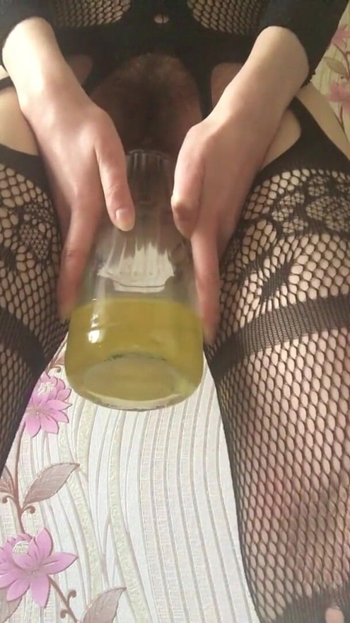 A brunette in a sexy bodysuit peeing in a jar with her hairy pussy from morning to evening | Clip 1