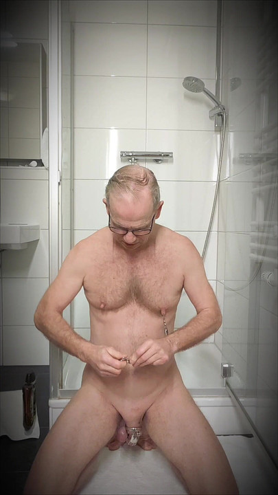 The naked slave clamps his tit clamps on and gets even hornier.