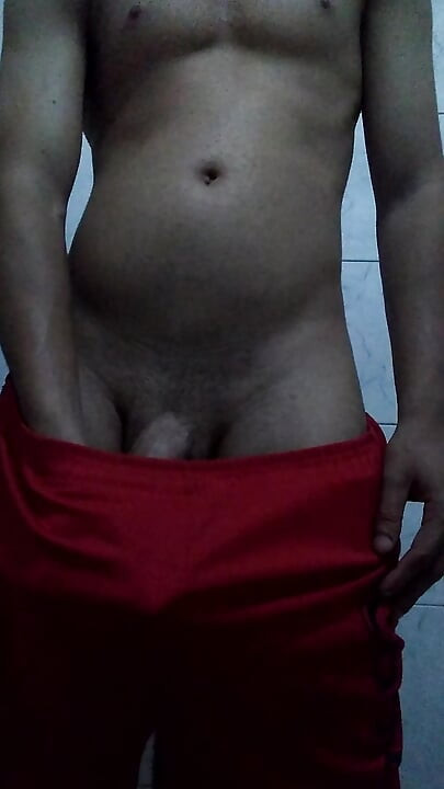 Skinny young guy masturbating big thick cock in red shorts