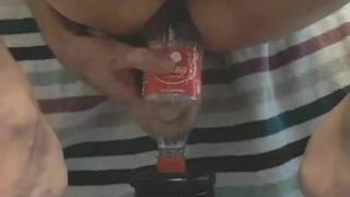 Accroupi sur une bouteille de coca de 500 ml. insertion anale