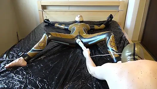 Latex Danielle is attached to the bed and masturbated with the massage vibrator