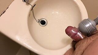 Kleiner Penis mit einem Vibratorärmel kommt und pisst auf das Waschbecken