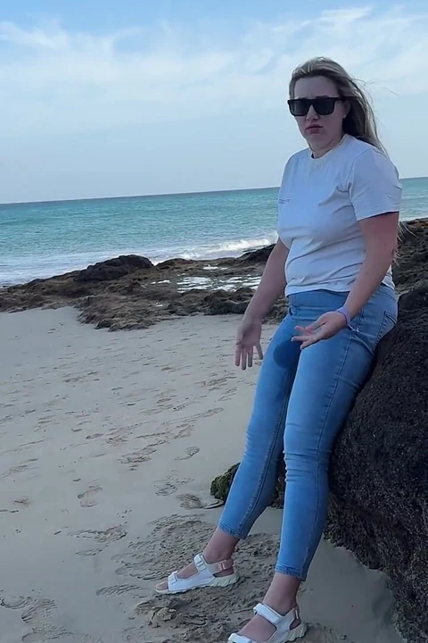 在海滩上穿着紧身牛仔裤撒尿