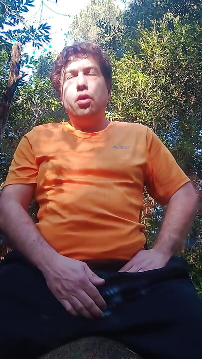 Boy in the woods sitting on a tree trunk pees and then jerks off with saliva coming from his mouth at the end
