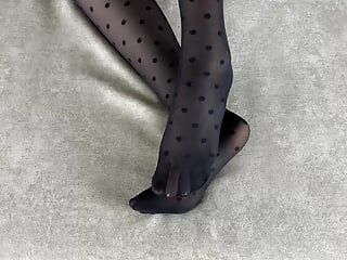 Ein Mädchen in schwarzen Nylonstrumpfhosen streichelt ihre Beine in verschiedenen Posen