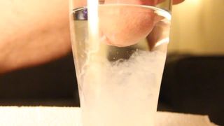 Close-up cumshot of circumcised cock in glass of water