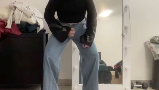 Ausgestelltes Palazzo-Jeans-Sissy mit weitem Bein, in schwarzer Jacke, masturbiert und wartet darauf, dass eine Herrin Schwänze und BDSM lutscht