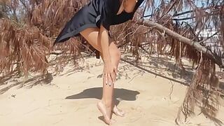 La ragazza teenager nuda mostra la figa, le gambe ed i piedi, feticismo delle gambe in una spiaggia nudista pubblica all'aperto