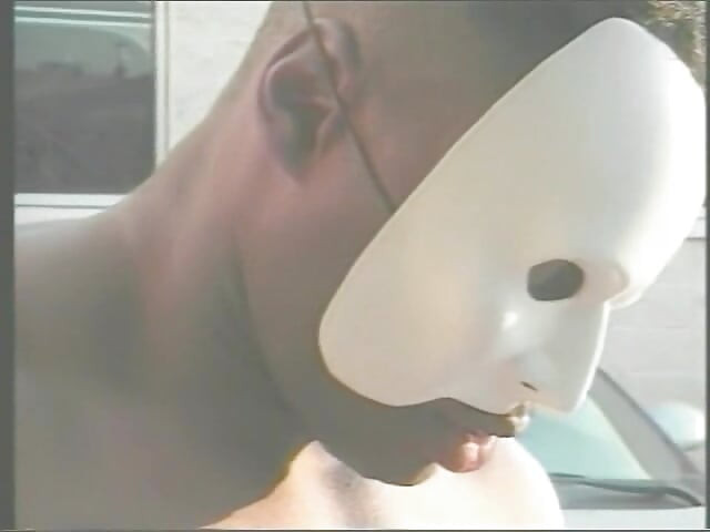 Muscular Stranger in White Superhero Mask Drills Ebony Chick on the Parking of Shopping Mall