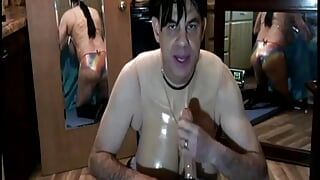 Transexual with big fake boobs titfucks and gives blowjob to huge dildo while wearing metallic panties.