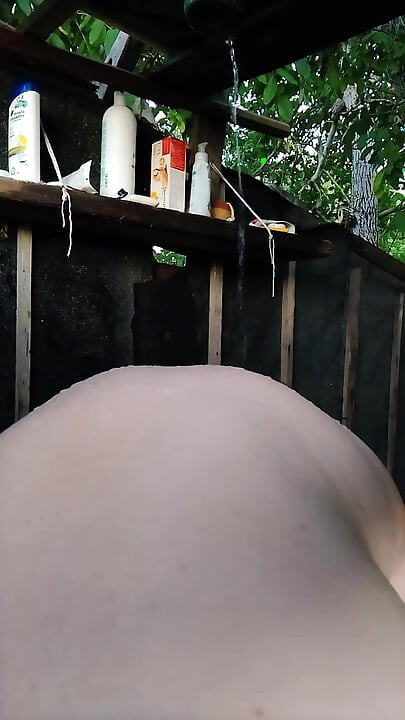Sexy Tanya lavando en la ducha de verano al aire libre del pueblo